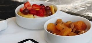 Two bowls of fresh fruit on a counter beside a service tablet