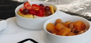 Two bowls of fresh fruit on a counter beside a service tablet